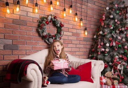 Little school age girl with a Christmas gift in her hands.の写真素材