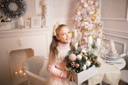 Merry Christmas celebration. Beautiful little girl in a dress lying near the Christmas tree. Winter holidays.の写真素材