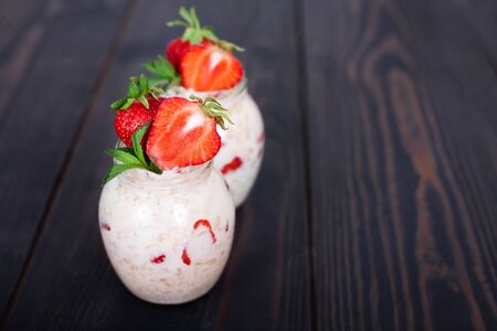 Oatmeal with yogurt and strawberries on a dark wooden background. Healthy eatingの写真素材