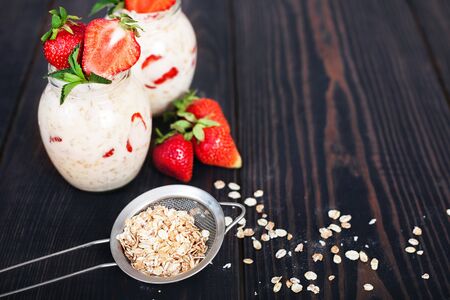 Oatmeal with yogurt and strawberries on a dark wooden background. Healthy eatingの写真素材