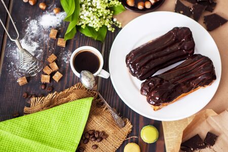 Fresh homemade eclairs with chocolate on the kitchen table close-up. French pastries.の写真素材