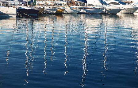 Reflection from yacht masts on the water in the port. Water texture with reflections.の写真素材