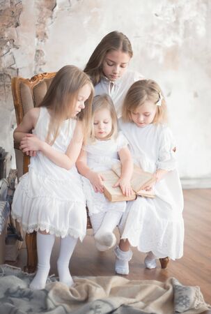 Four girls friends or sisters read a book at home. Studio, retro style.の写真素材
