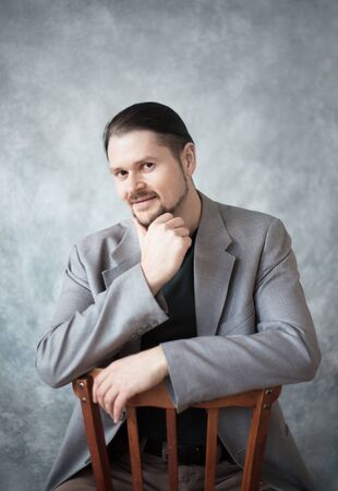 Portrait of a young man in a business jacket on a gray background in the studio. Classic portrait, casual style.の写真素材