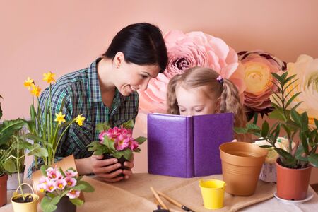 Cute child girl helps her mother to care for plants.の写真素材