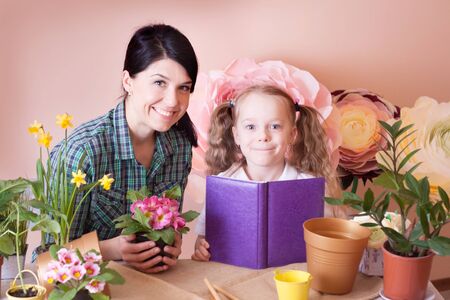 Cute child girl helps her mother to care for plants.の写真素材