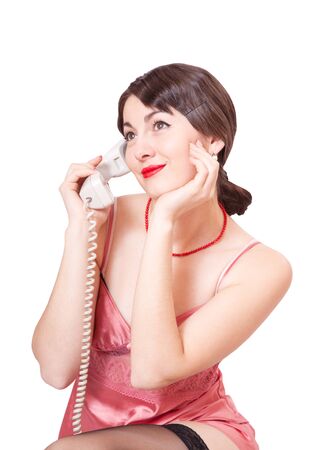 Young beautiful woman with an old phone in hand, isolated on white backgroundの写真素材