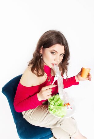 Young beautiful woman eating a plastic bag as a concept of plastic contaminated food. Ecology and healthy eating concept. Studio shot.. Hight quality photoの写真素材