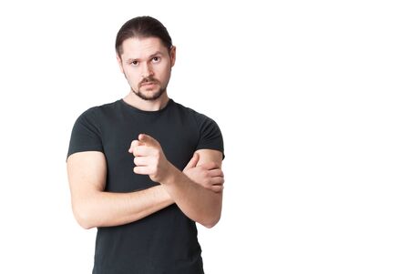 Young serious man points a finger in front of himself. Isolated on a white background.の写真素材