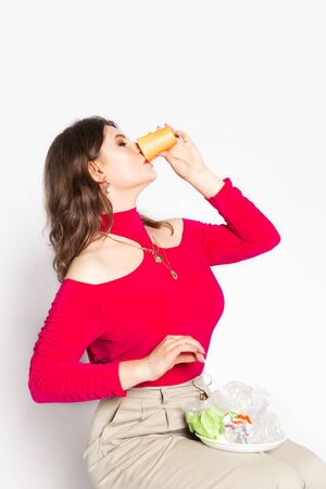 Young beautiful woman eating a plastic bag as a concept of plastic contaminated food. Ecology and healthy eating concept. Studio shot.. Hight quality photoの写真素材