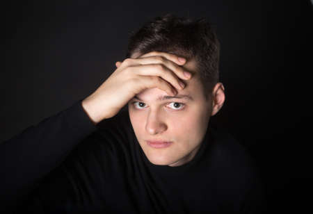 Portrait of an attractive man in the studio on a black background. Young serious guy.の写真素材
