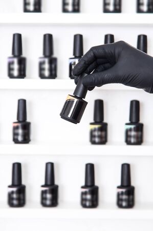 Manicurist selects the color of nail polish, hand in glove closeup, studio.の写真素材