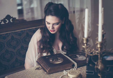 Young woman looks at a photo album. Vintage style, retro interior.の写真素材