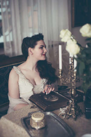 Young woman looks at a photo album. Vintage style, retro interior.の写真素材