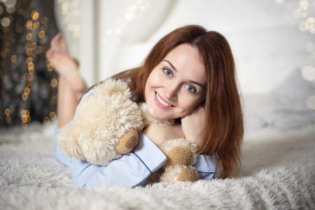 Young beautiful woman in pajamas in the bedroom. Winter holiday.の写真素材