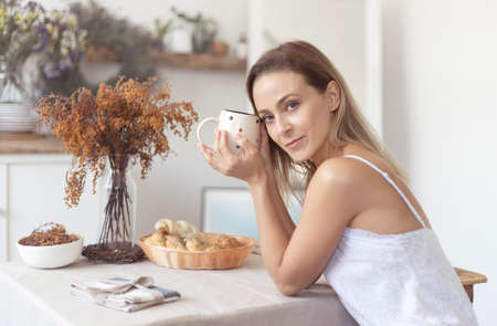 Young beautiful woman having breakfast in the morning in the kitchen.の写真素材
