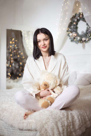 Young beautiful woman in pajamas in the bedroom. Winter holiday.の写真素材