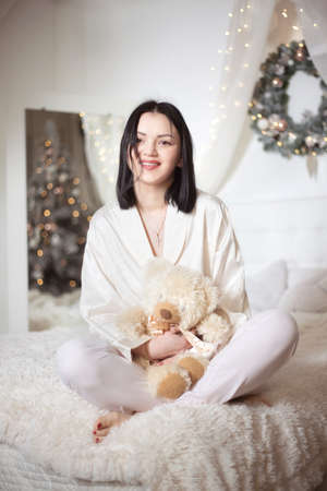 Young beautiful woman in pajamas in the bedroom. Winter holiday.の写真素材