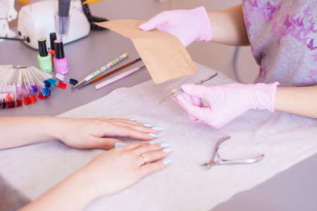 The manicurist opens an individual package with tools. Disinfection and sterilization. Safety. Close-up.の写真素材