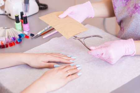 The manicurist opens an individual package with tools. Disinfection and sterilization. Safety. Close-up.の写真素材