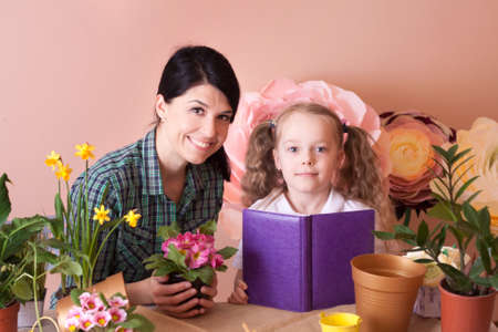 Mom and daughter take care of indoor flowers. Studio photo. Happy family on a studio.の写真素材