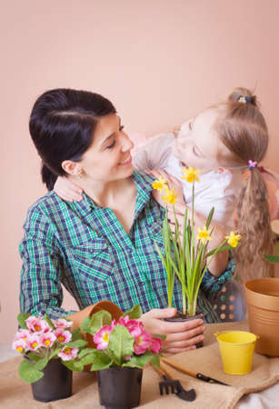 Mom and daughter take care of indoor flowers. Studio photo. Happy family on a studio.の写真素材