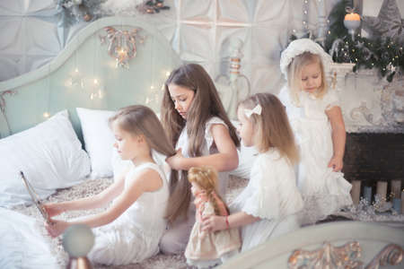 Little girls play in the bedroom in the morning before Christmas. The concept of family, sisterhood, friendship. Winter holidays, Christmas, New Year.の写真素材