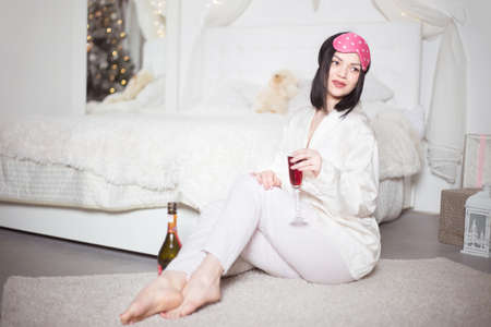 Young beautiful woman in pajamas with champagne in the bedroom. Winter holidays. High quality photoの写真素材