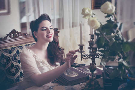 Young woman looks at a photo album. Vintage style, retro interior.の写真素材