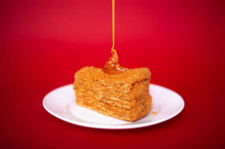 Classic cake with caramel cream on a red background. Serving, close-up.の写真素材
