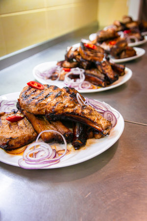 BBQ grill ribs served in portions in the restaurant kitchen. Plates with meat dish close-up.の写真素材