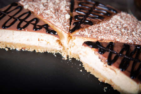 Sliced cheesecake with cocoa and chocolate sauce close-up on the table.の写真素材