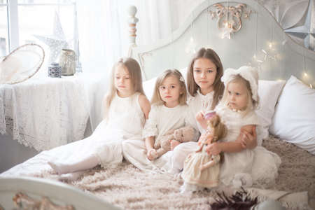 Little girls sisters in the morning in bed. Vintage style, Christmas holidays. Studio photoの写真素材