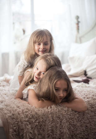 Little girls sisters in the morning in bed. Vintage style, Christmas holidays. Studio photoの写真素材