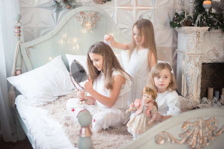 Little girls play in the bedroom in the morning before Christmas. Winter holidays, Christmas, New Year.の写真素材