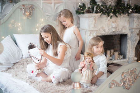 Little girls play in the bedroom in the morning before Christmas. Winter holidays, Christmas, New Year.の写真素材