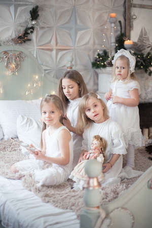 Little girls play in the bedroom in the morning before Christmas. The concept of family, sisterhood, friendship. Winter holidays, Christmas, New Year.の写真素材