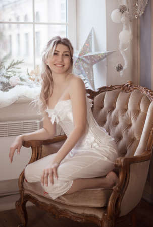 Cute beautiful woman sitting in the armchair, vintage style. Winter holidays.の写真素材