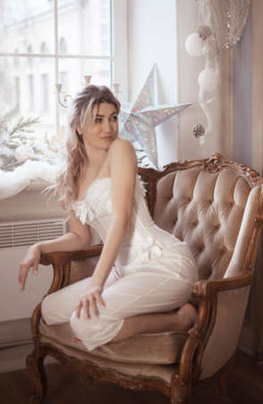 Cute beautiful woman sitting in the armchair, vintage style. Winter holidays.の写真素材