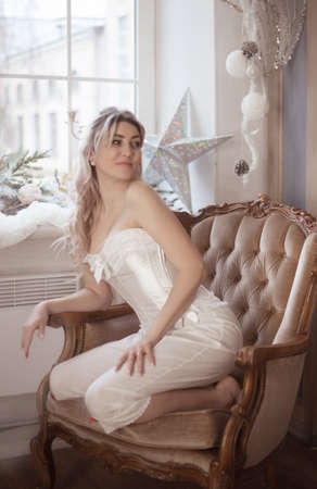 Cute beautiful woman sitting in the armchair, vintage style. Winter holidays.の写真素材