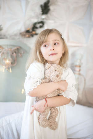 Little girl and her teddy bear in the morning in the bedroom. Retro style. Winter holidays.の写真素材
