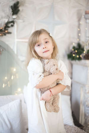 Little girl and her teddy bear in the morning in the bedroom. Retro style. Winter holidays.の写真素材