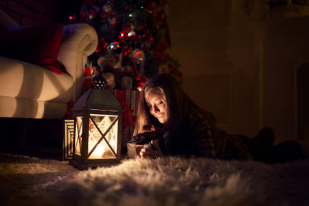 A girl near a Christmas tree with a decorative lantern in her hands, New Year and Christmas.の写真素材