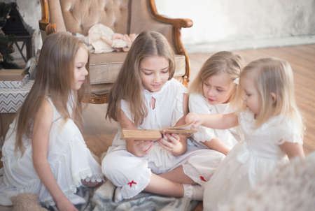 Sister girls are reading a book in the children's room. Christmas and winter holidays. High quality photoの写真素材