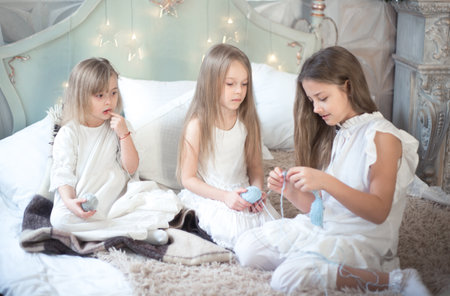 Little girls sisters or friends are doing needlework in the bedroom. Retro style.の写真素材
