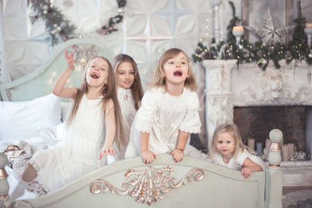 Little girls sisters in the morning in bed. Vintage style, Winter Holidays, Christmas and New Year. Studio photo.の写真素材