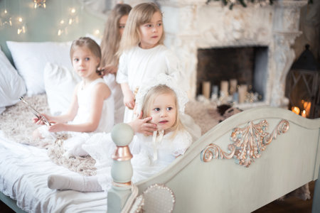 Little girls play in the bedroom in the morning before Christmas. The concept of family, sisterhood, friendship. Winter holidays, Christmas, New Year.の写真素材