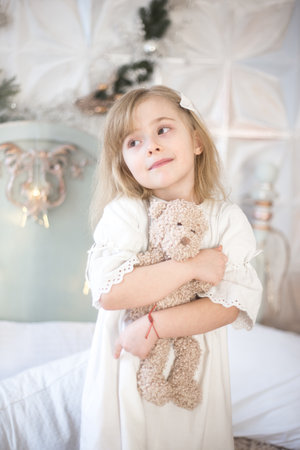 Little girl and her teddy bear in the morning in the bedroom. Retro style.の写真素材