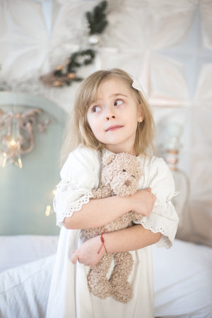Little girl and her teddy bear in the morning in the bedroom. Retro style.の写真素材