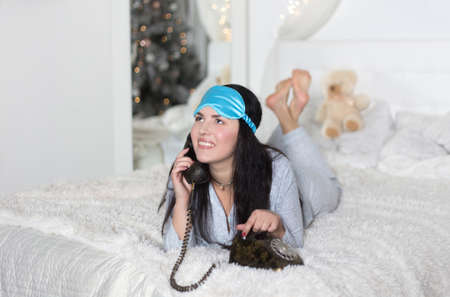 Young beautiful woman lies on the bed with a vintage telephone. Communication and communication, retro.の写真素材
